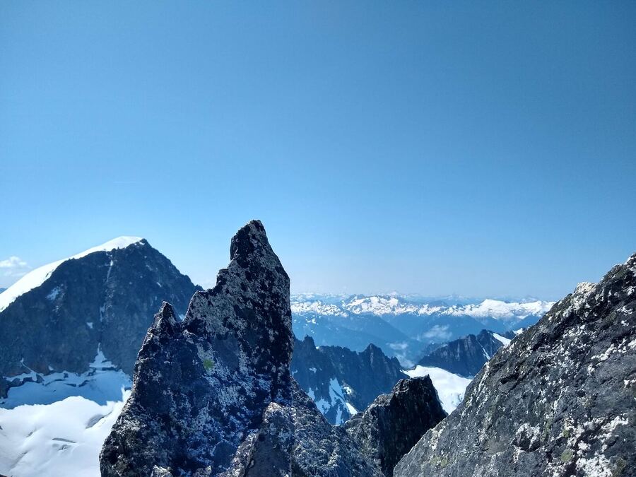 A dark pinnacle beside a peak, a sea of cloud far below