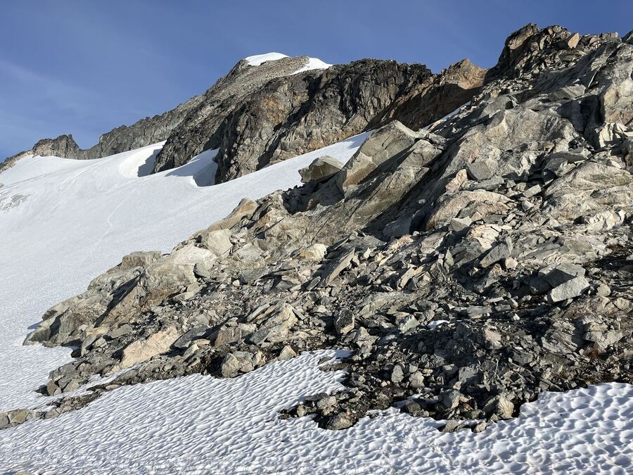 Grey rocks and a snowfield under a pale sky